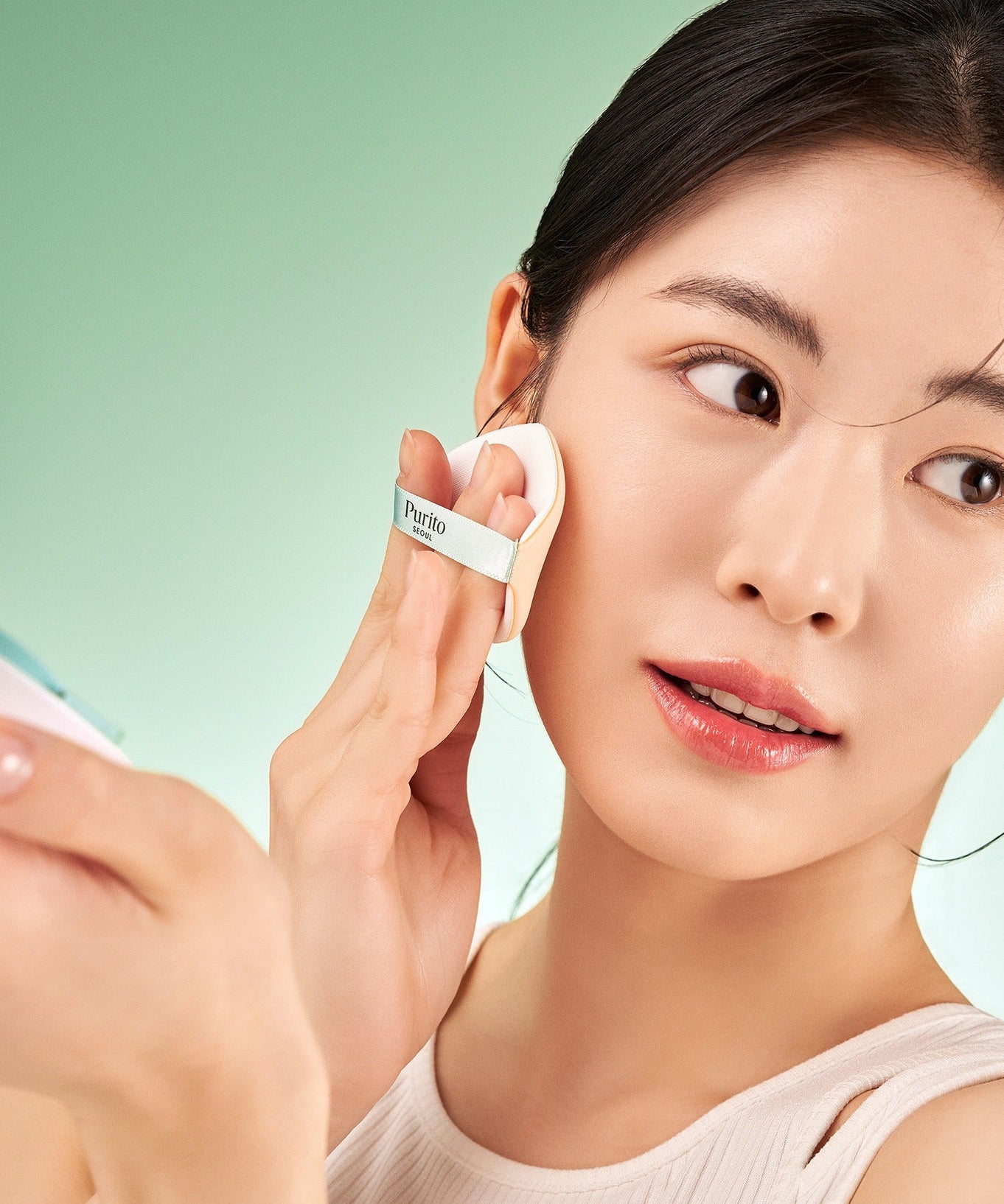 Person applying PURITO Wonder Relief Celtella BB Cushion 15g using compact mirror.
