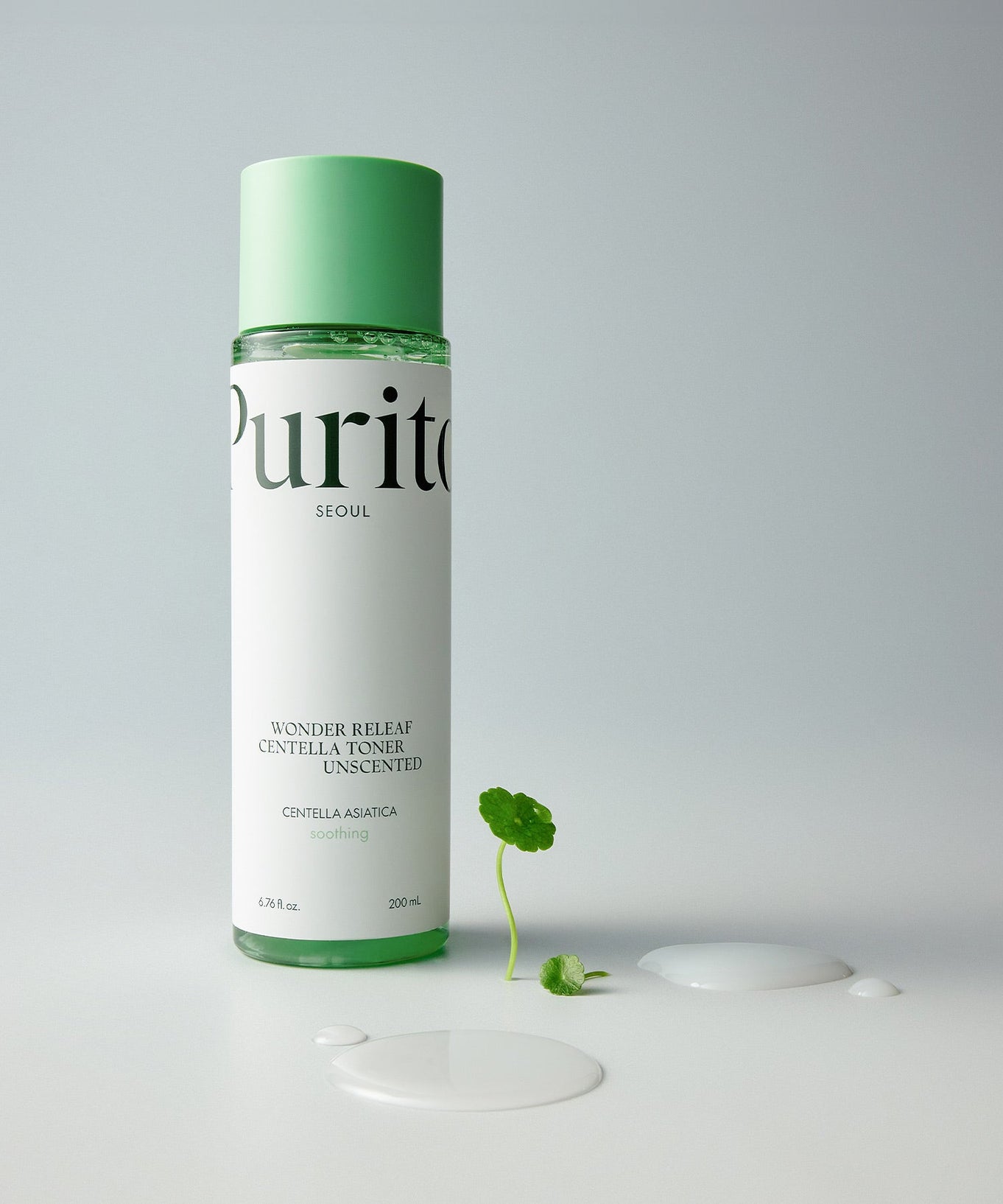 PURITO Wonder Relief Centella Toner Unscented 200ml bottle with centella asiatica leaf and spilled toner beside it.