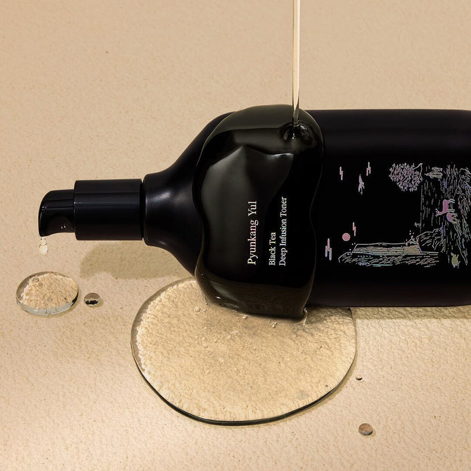 Bottle of PYUNKANG YUL Black Tea Deep Infushion Toner 130ml with spilling liquid, showcasing premium skincare product on beige background.