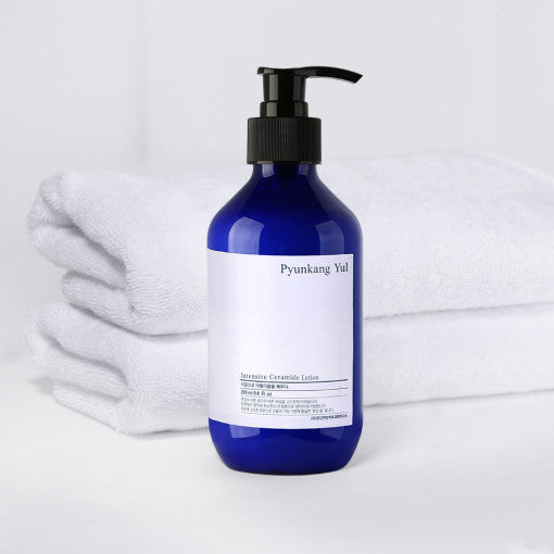 PYUNKANG YUL Intensive Ceramide Lotion bottle in blue against a background of white towels, highlighting skincare benefits.