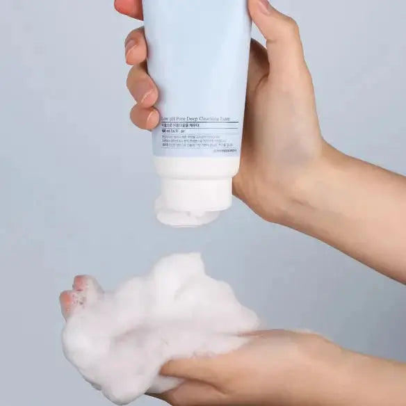 Hands dispensing PYUNKANG YUL Mildly Acidic Pore Deep Cleansing Foam 100ml with foam lathering, close-up view.