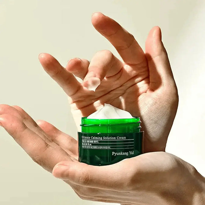 Hand holding PYUNKANG YUL Ultimate Soothing Solution Cream 30ml jar