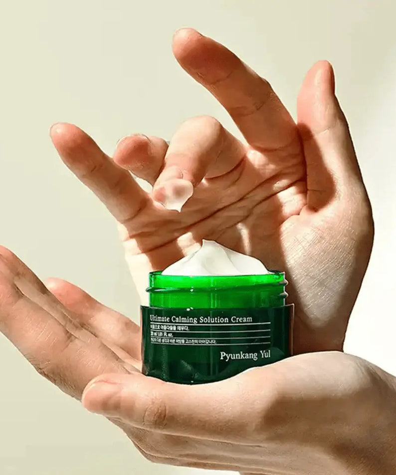 Hand holding PYUNKANG YUL Ultimate Soothing Solution Cream 30ml jar