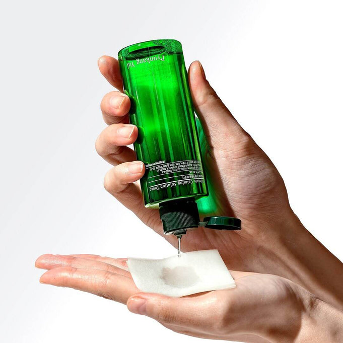 Hands using PYUNKANG YUL Ultimate Soothing Solution Toner 110ml on cotton pad