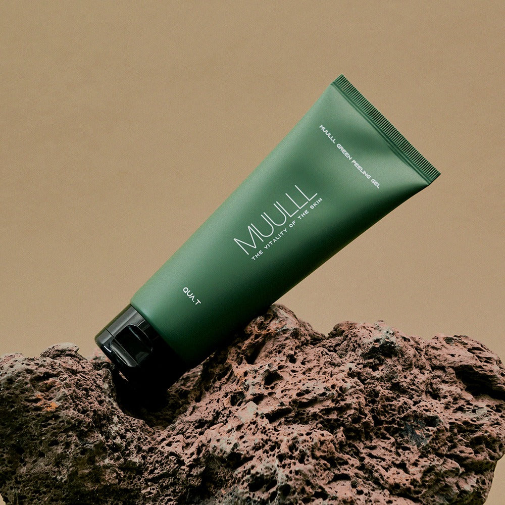 QUA-T Green Peeling Gel 150ml tube on a natural rock surface, highlighting skincare packaging.