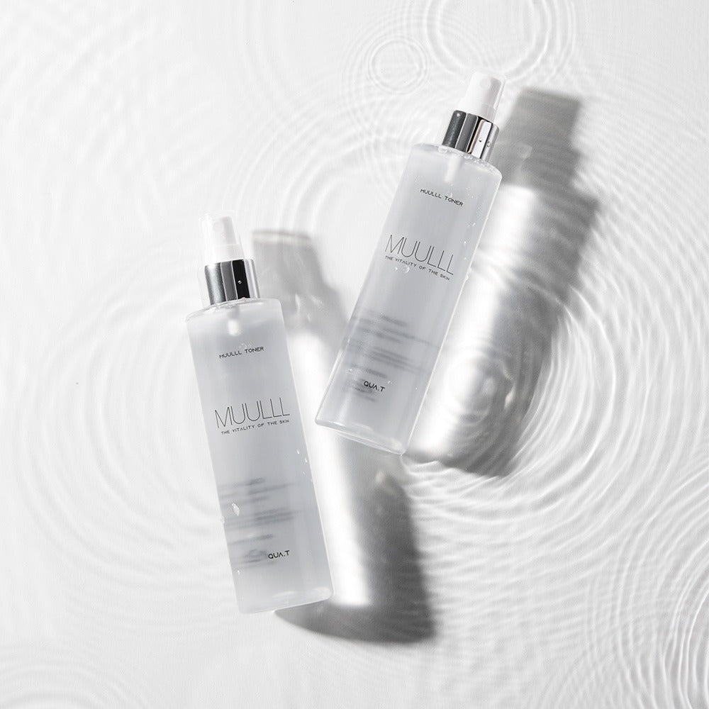 QUA-T Toner 200ml bottles placed on a rippled water surface, showcasing premium skincare packaging.