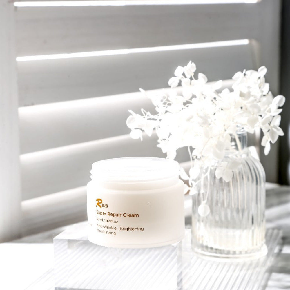 R828 Super Repaire Cream 50 ml displayed with a white floral arrangement in the background.
