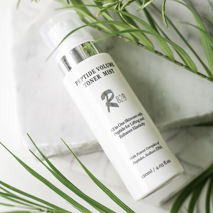 R828 Peptide Volume Toner Mist bottle on white background with green leaves