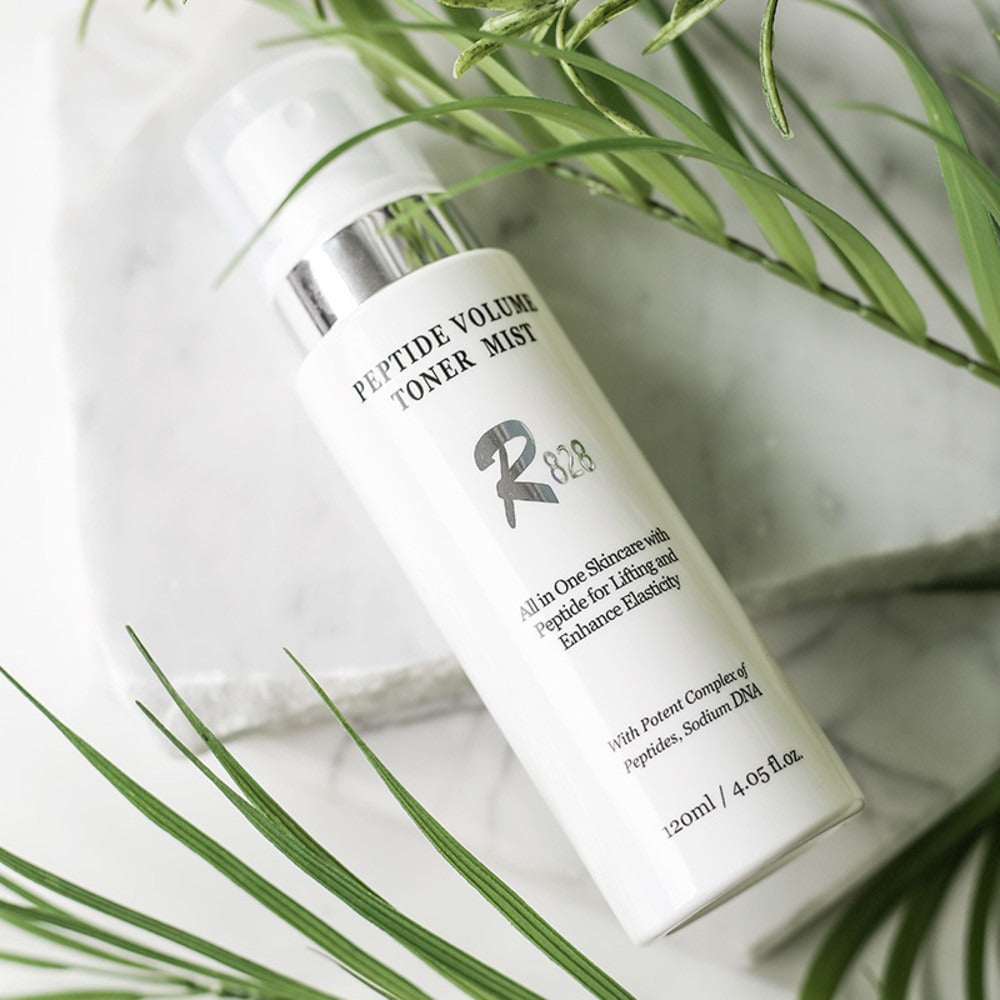 R828 Peptide Volume Toner Mist bottle on white background with green leaves