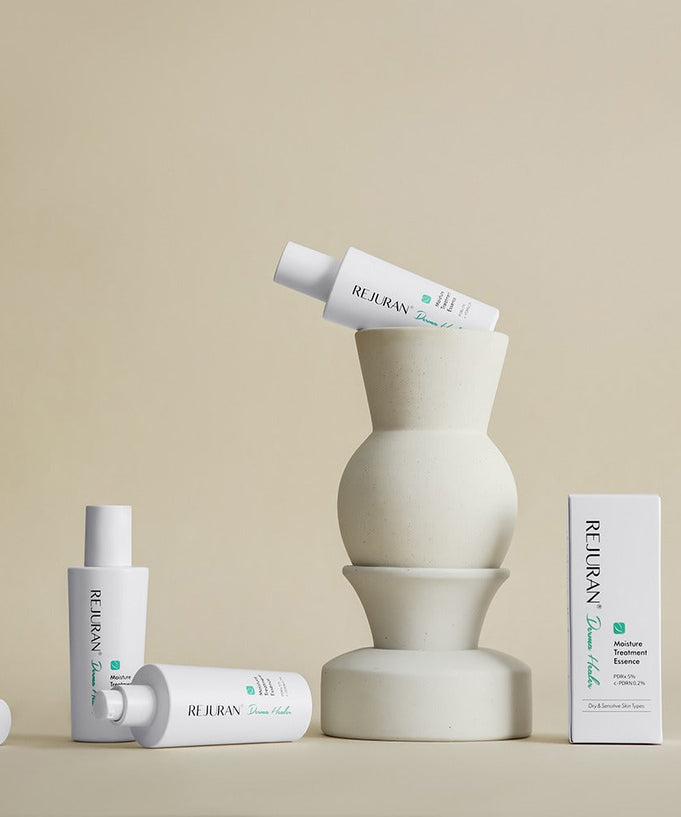 Collection of REJURAN Derma Healer Moisture Treatment Essence 70g bottles displayed artistically on a beige background.