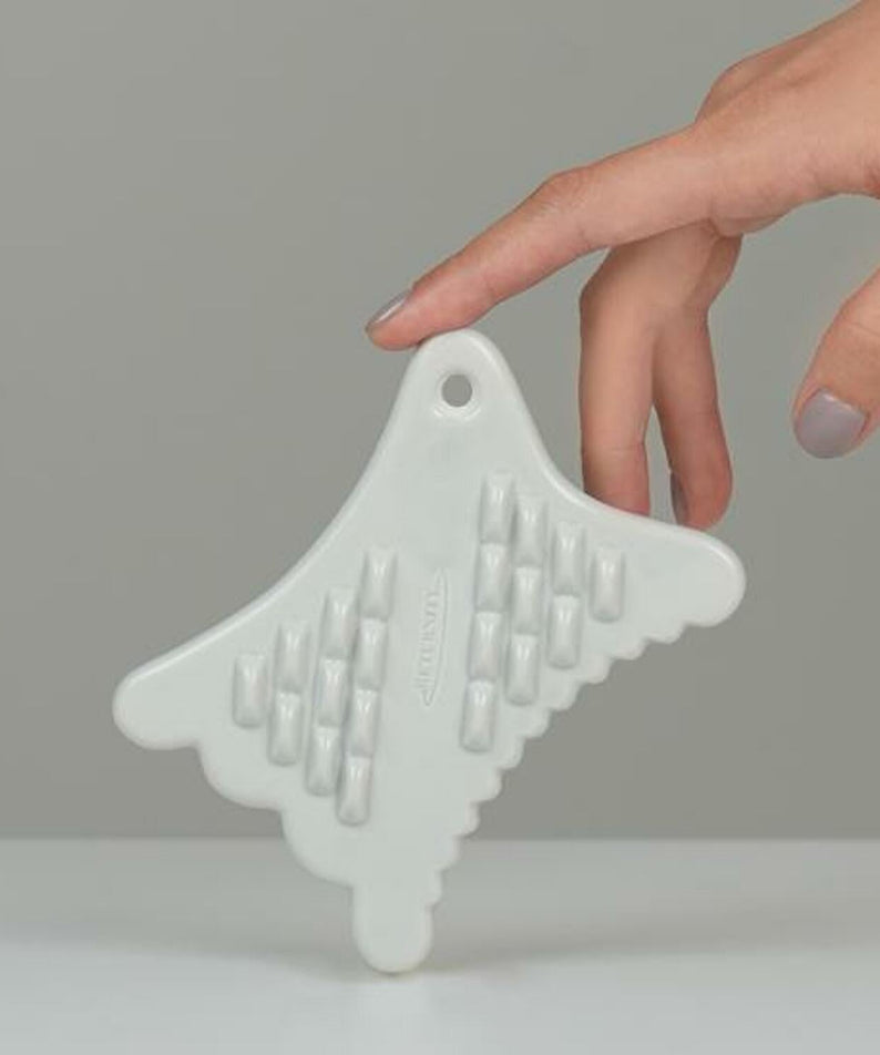 Hand holding RETURNITY Mini Guasha tool on a gray background, showcasing its design and features for effective skincare treatment.