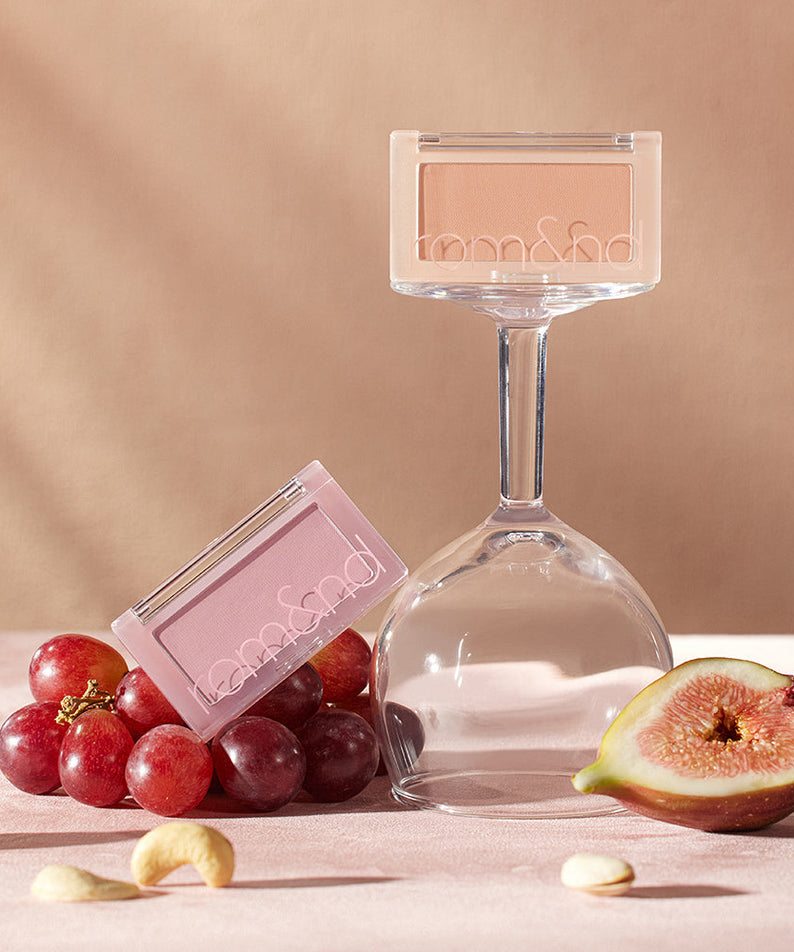 ROMAND Better Than Cheek Blush in natural setting with grapes and fig, showcasing elegant makeup design.