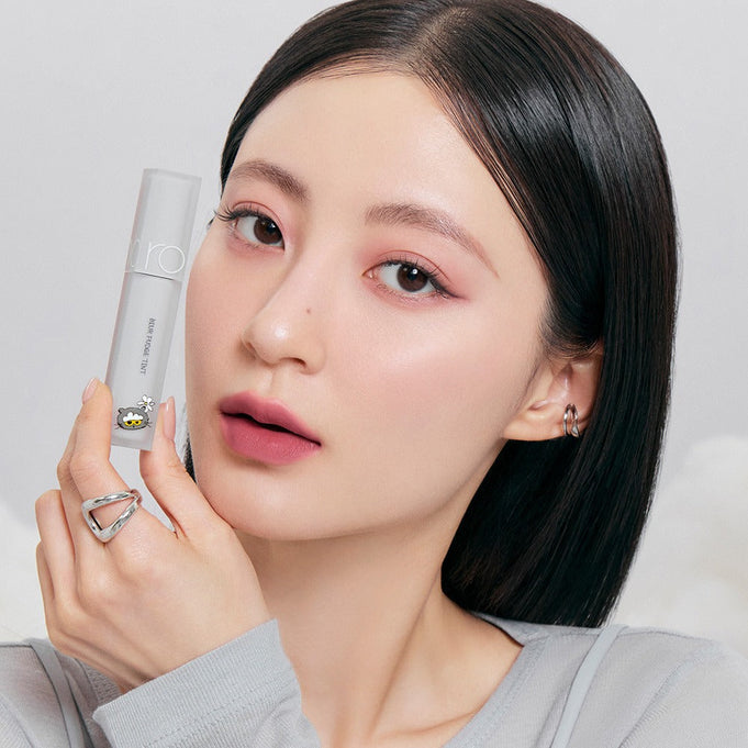 Woman holding ROMAND x Joanne Friends Blur Fudge Tint, showcasing the lip tint color and packaging.