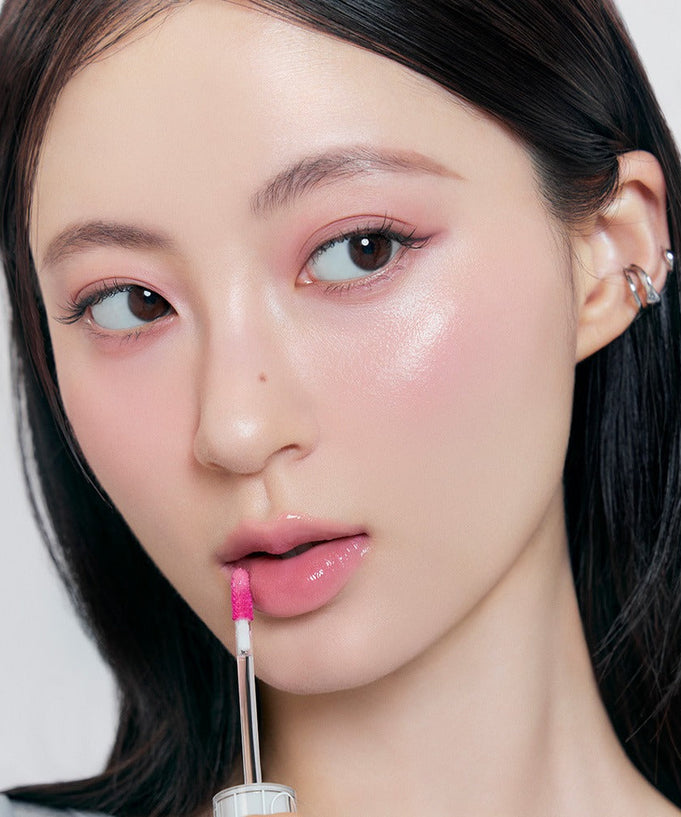 Model applying ROMAND x Joanne Friends The Juicy Lasting Tint for a glossy lip finish.