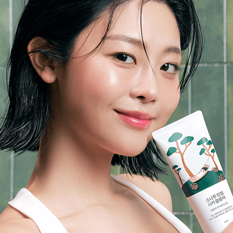 Smiling woman holding ROUND LAB Pine Calming Cica Cleanser 150ml in her hand