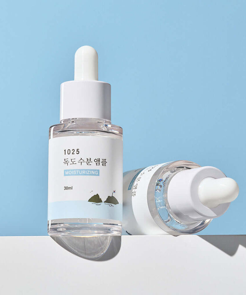 ROUND LAB 1025 Dokdo Ampoule 45g bottle on a blue background demonstrating moisturizing skincare serum.