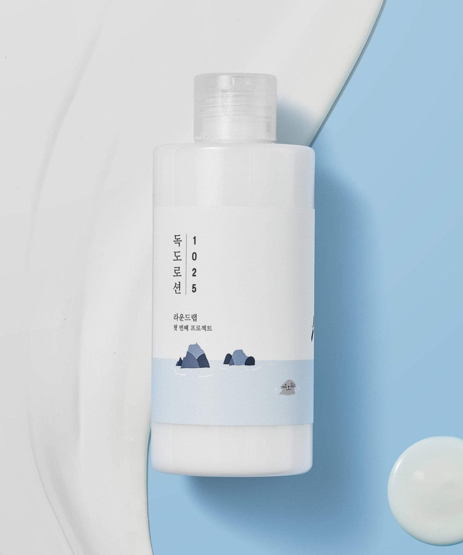 ROUND LAB 1025 Dokdo Lotion 400ml bottle on blue and white background with lotion texture