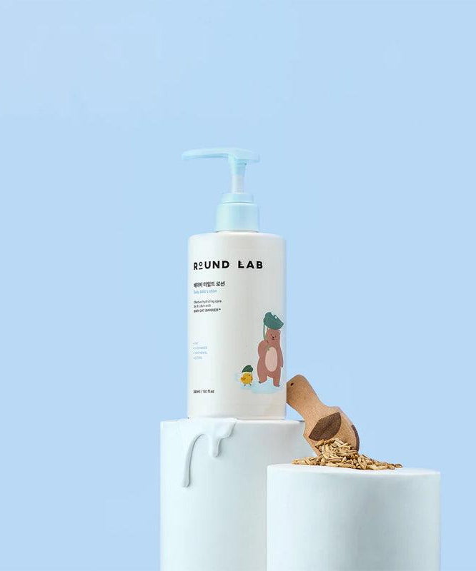 ROUND LAB Baby Mild Lotion 300ml bottle displayed with natural ingredients on a light blue background.