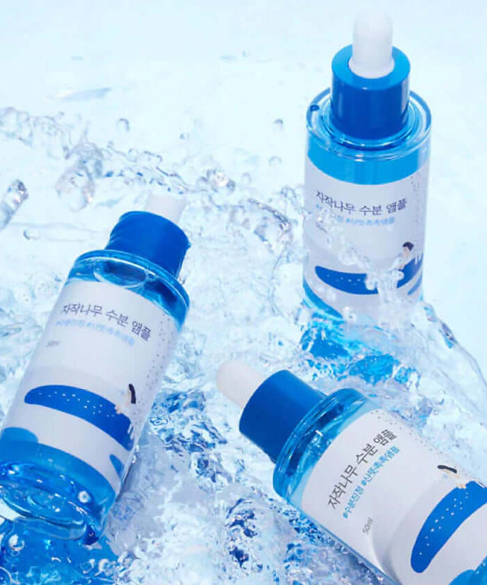 Three bottles of ROUND LAB Birch Moisture Ampoule 50ml on a watery surface