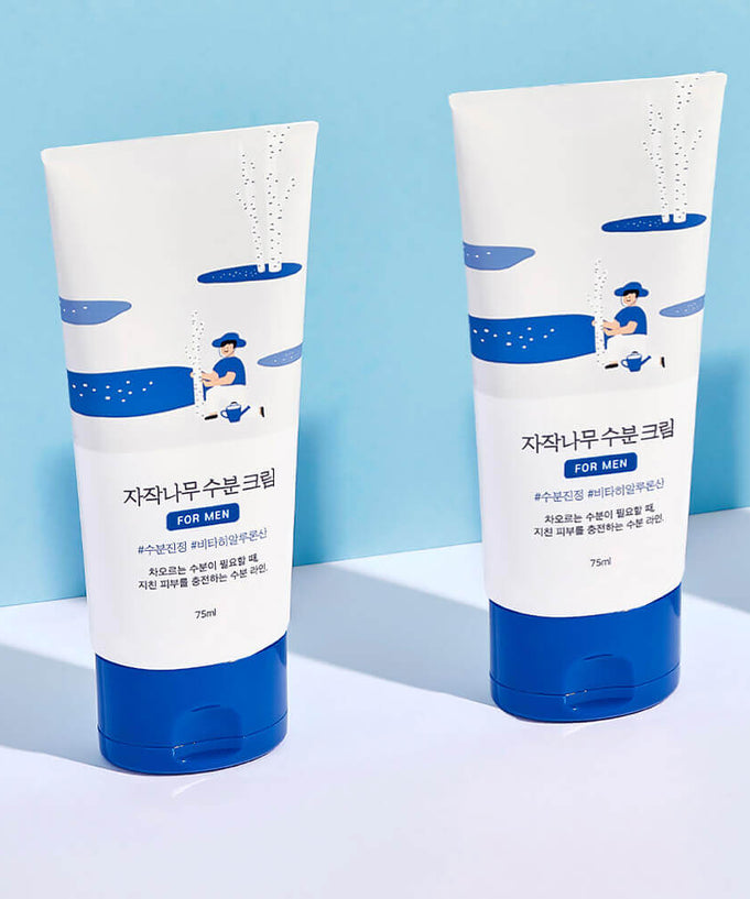 Two tubes of ROUND LAB For Men Birch Moisture Cream 75ml placed against a blue background.