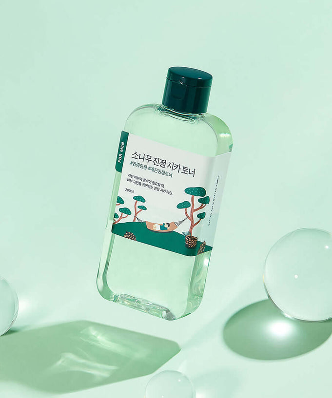 ROUND LAB For Men Pine Calming Cica Toner 200ml bottle on green background with bubbles.