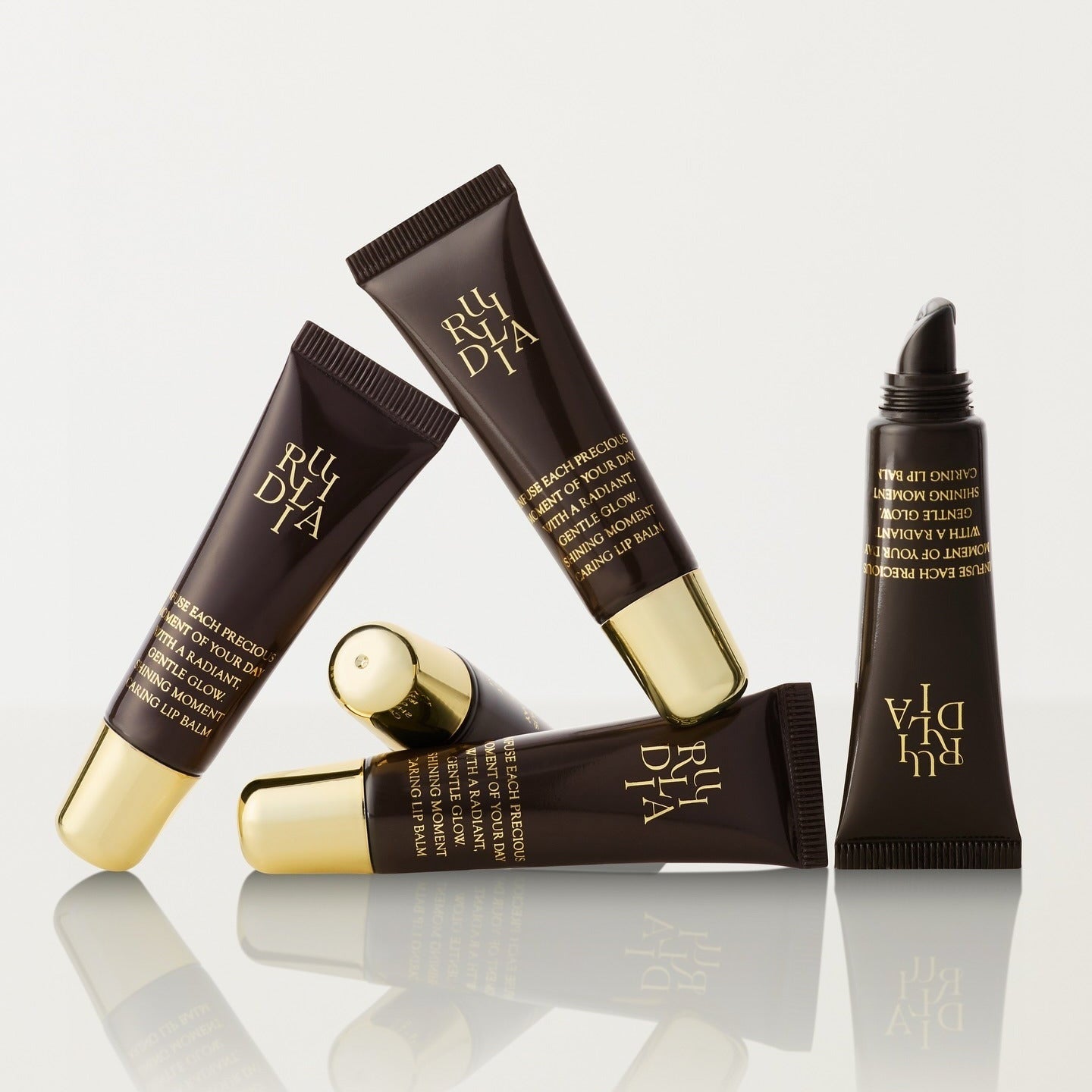 RULIDIA Shining Moment Caring Lip Balm 8g tubes arranged artistically on a white background.