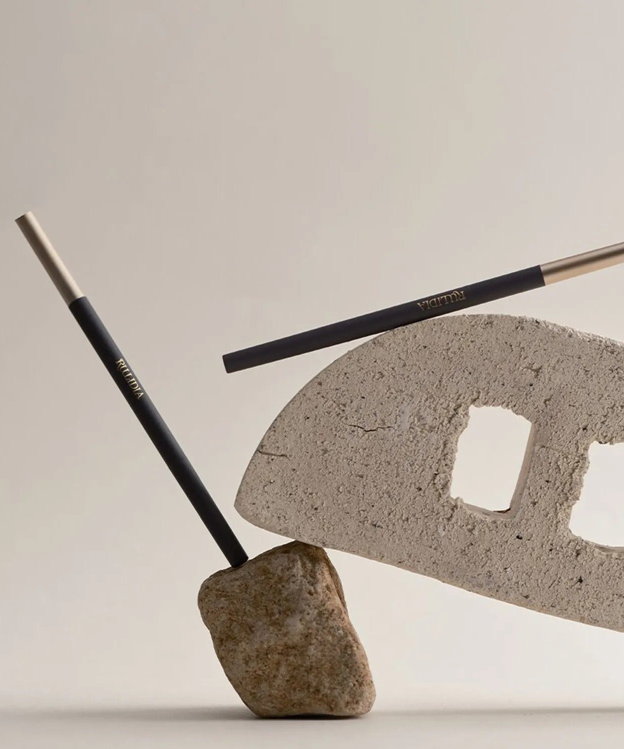 RULIDIA Easy Detail Brow pencils placed artistically on stone and brick backdrop, showcasing sleek design and precision for ideal brow definition.