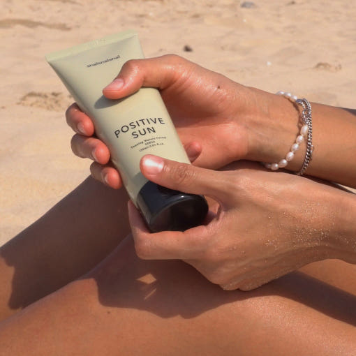 SHAISHAISHAI Positive Sun Tanning Watery Cream SPF22 50ml held by person on a beach