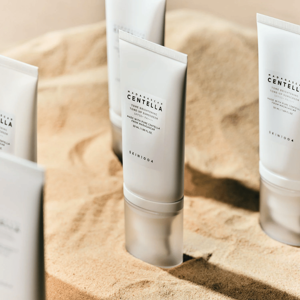 SKIN1004 Madagascar Centella Tone Brightening Tone-Up Sunscreen 50ml displayed on sand background.
