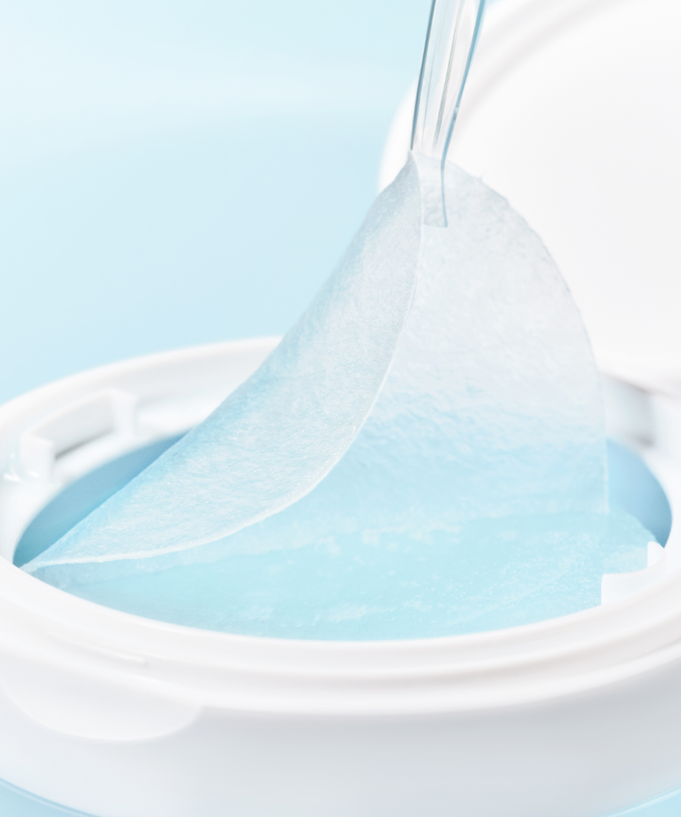 Close-up of SKIN1004 Madagascar Centella-Hyalu-Cica Jelly Fit Ampoule Pads (60 sheets) in a white container with a pad being removed.