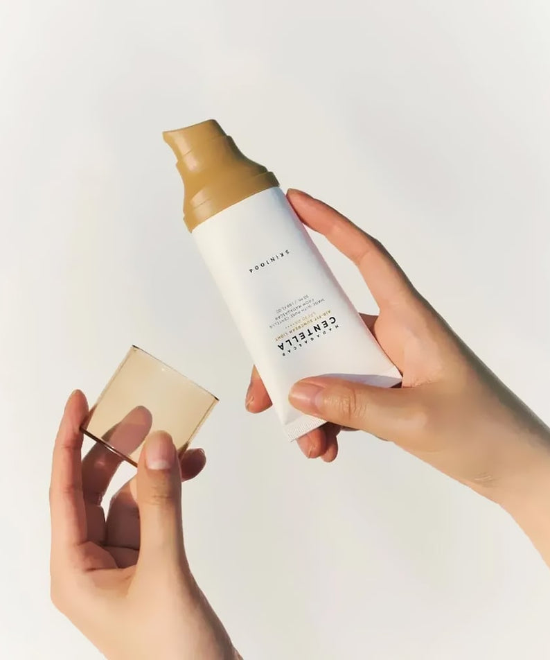 Hands holding SKIN1004 Madagascar Centella Air-fit Sunscreen Light 50ml with cap