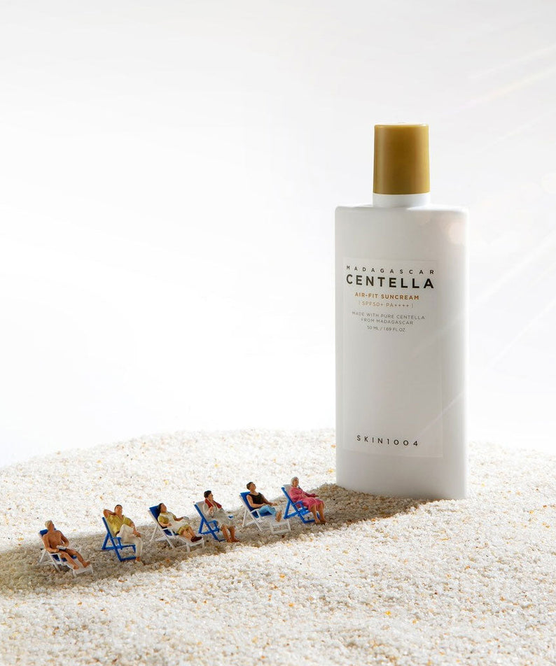 SKIN1004 Madagascar Centella Air-fit Sunscreen Plus 50ml on a sandy beach scene with miniature sunbathers