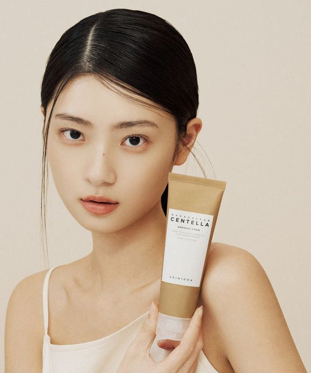 Woman holding tube of SKIN1004 Madagascar Centella Ampoule Foam 125ml.