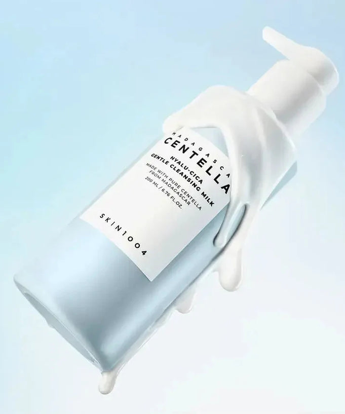 SKIN1004 Madagascar Centella Hyalur-Cica Gentle Cleansing Milk 200ml bottle with product spilling out, against a blue background.
