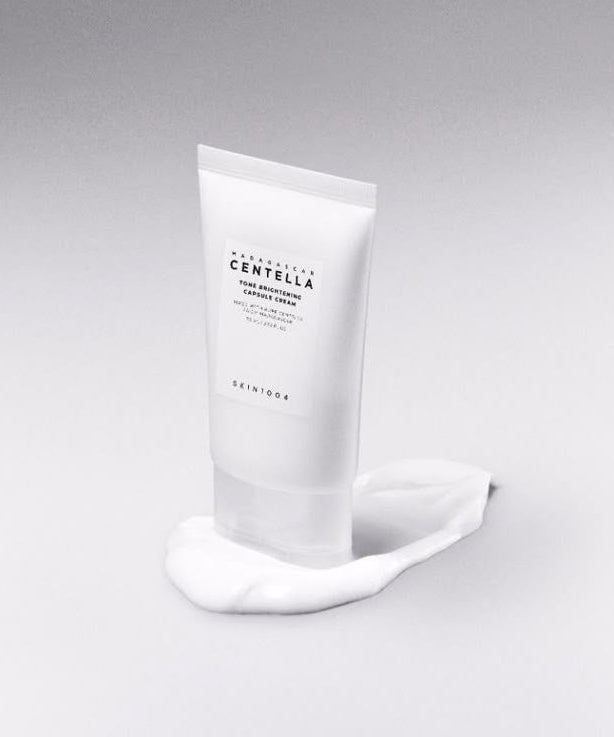 SKIN1004 Madagascar Centella Tone Brightening Capsule Cream 75ml in white tube on gray background showing creamy texture.