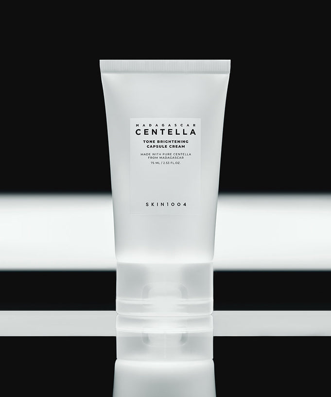 SKIN1004 Madagascar Centella Tone Brightening Capsule Cream 75ml in a sleek tube on reflective black surface.