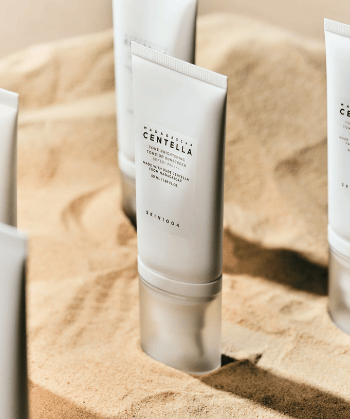SKIN1004 Madagascar Centella Tone Brightening Tone-Up Sunscreen 50ml displayed on sand background.