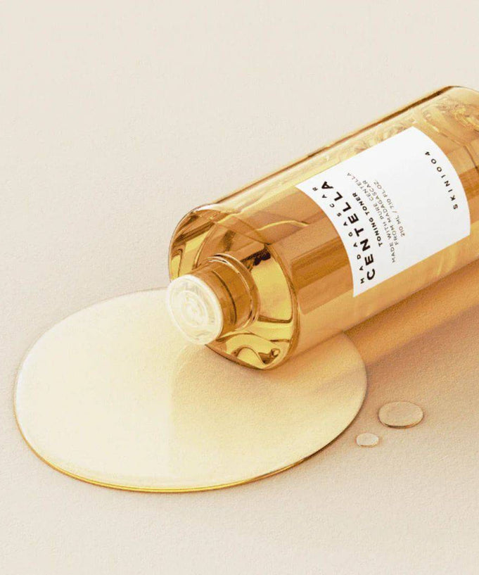 SKIN1004 Madagascar Centella Toning Toner 400ml bottle with liquid spread on a light background.