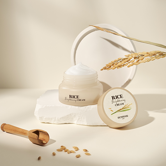 SKINFOOD Rice Brightening Cream 60ml in an open jar with rice grains and wheat stalks on a neutral background