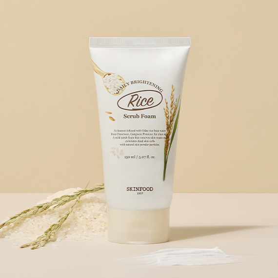 Image of SKINFOOD Rice Daily Brightening Scrub Foam 150ml tube with rice grains and scrub swatch on neutral background.