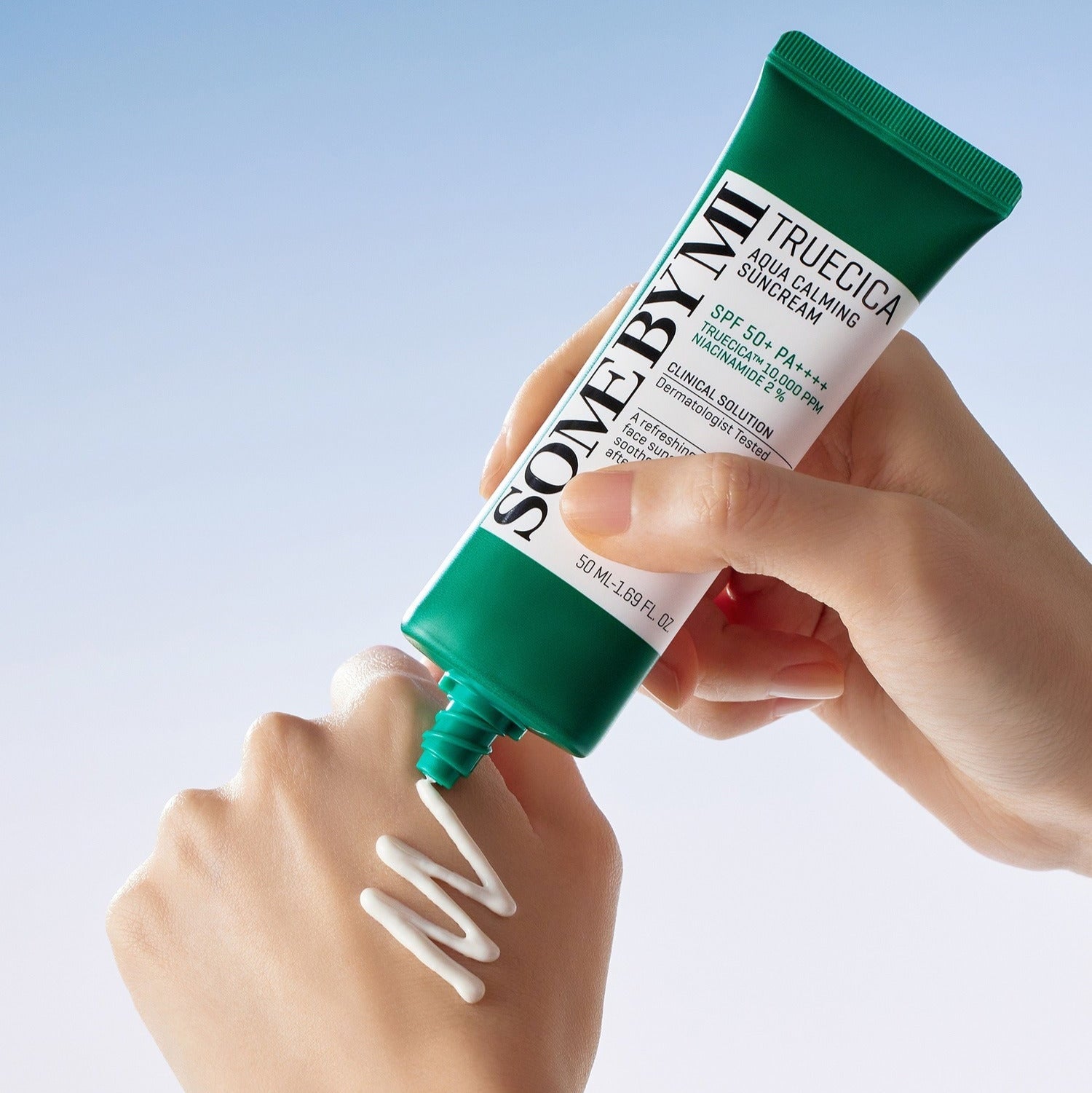 Applying SOME BY MI Truecica Aqua Calming Sun Cream 50ml on hand with cream texture displayed.