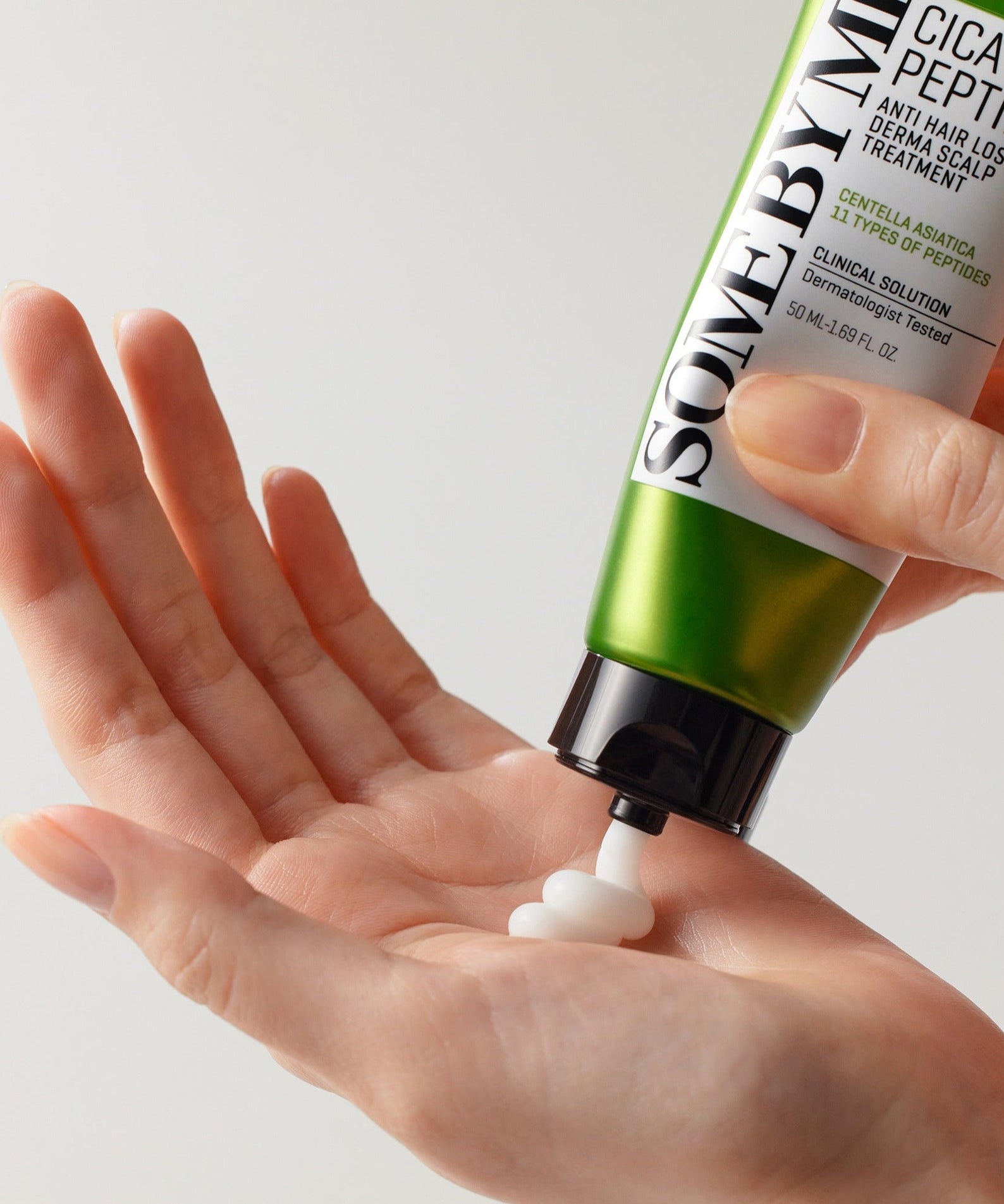 Applying SOME BY MI Cica Peptide Anti Hair Loss Derma Scalp Treatment 50ml from tube to hand for hair care