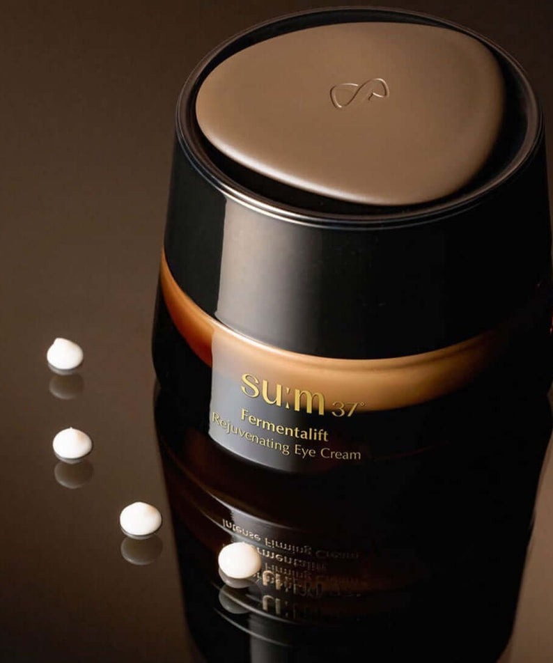 SU:M37 Fermentalift Rejuvenating Eye Cream 25ml golden brown jar with cream droplets on reflective surface