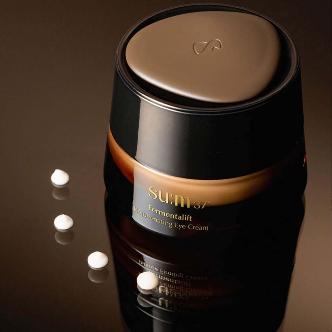 SU:M37 Fermentalift Rejuvenating Eye Cream 25ml golden brown jar with cream droplets on reflective surface