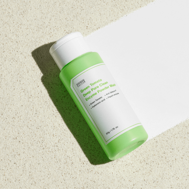 SUNGBOON EDITOR Green Tomato Deep Pore Clean Enzyme Powder Wash 50g in green bottle on sandy background.