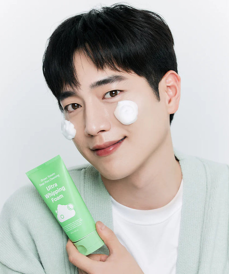 Person holding a tube of SUNGBOON EDITOR Green Tomato Pore Whipping Foam 120g with product applied on their face.