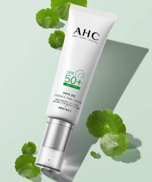 AHC Safe On Essence Sunscreen 50ml tube with SPF 50+, surrounded by green leaves for natural beauty protection.