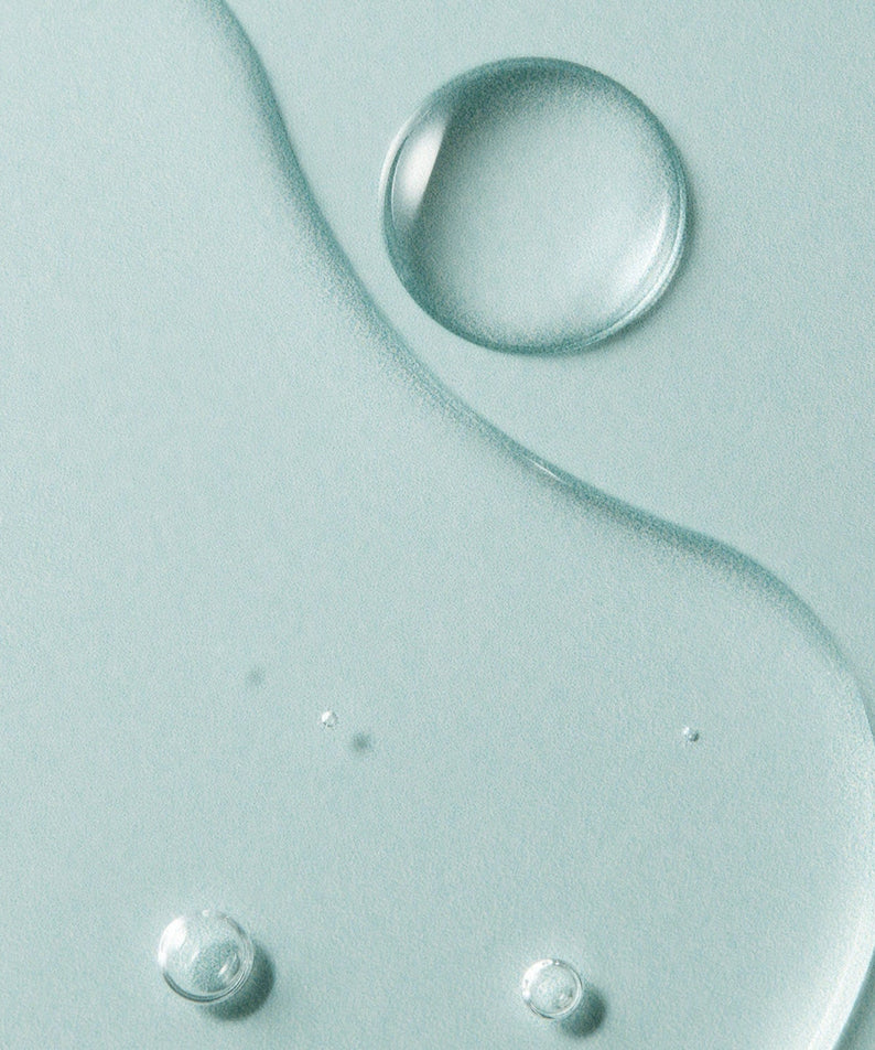Close-up texture of AROMATICA Super Tea Tree Clarifying Toner 200ML featuring droplets and fluid patterns.
