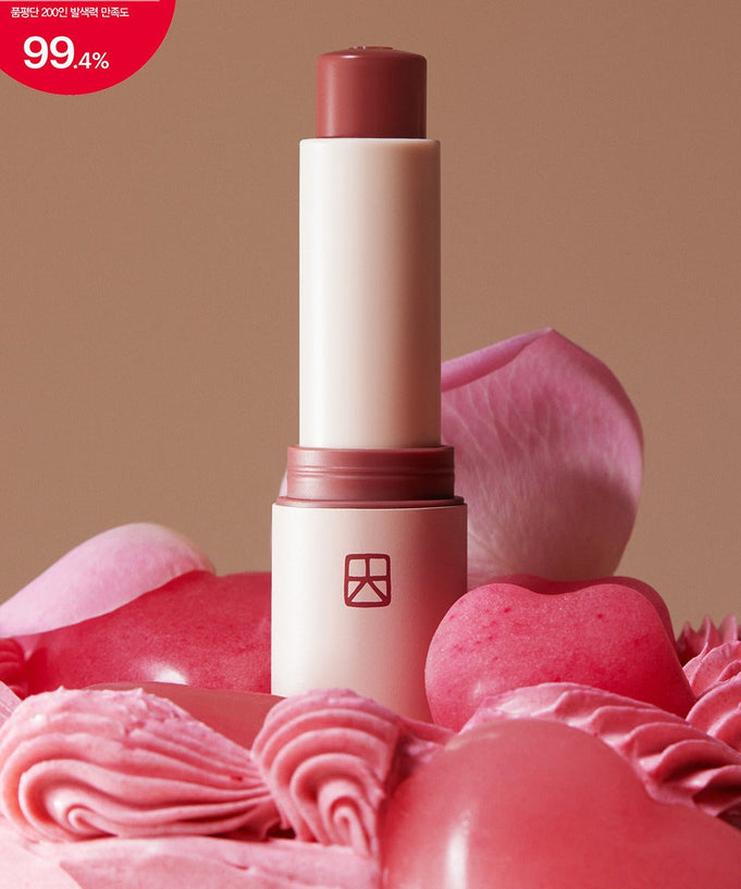 TALITHA KOUM Lipcure Balmtik lipstick surrounded by pink roses and swirls on a beige background.