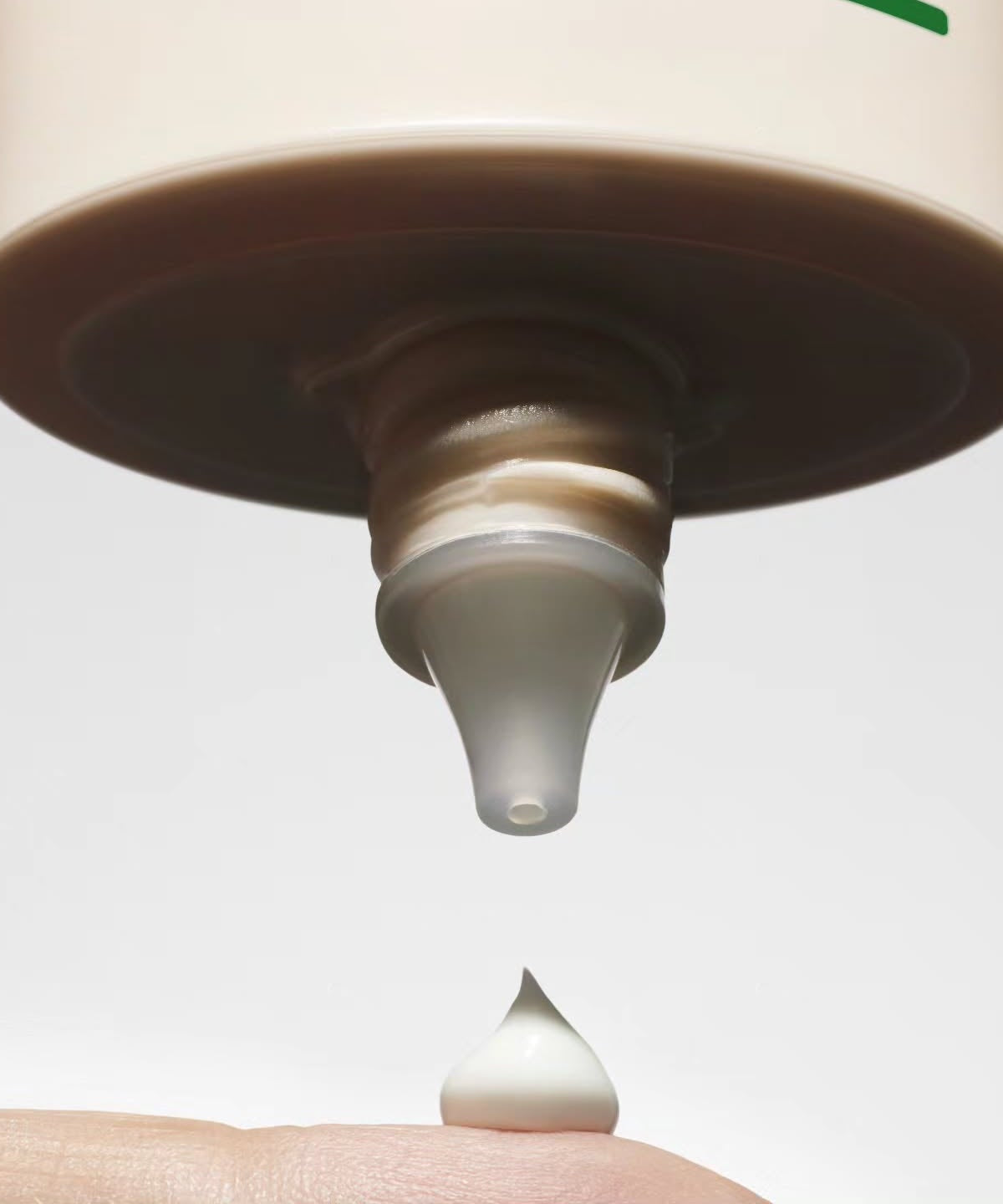 Close-up of TALITHA KOUM To go Essence Sun Screen 60ml being dispensed onto a finger, highlighting its creamy texture and packaging.